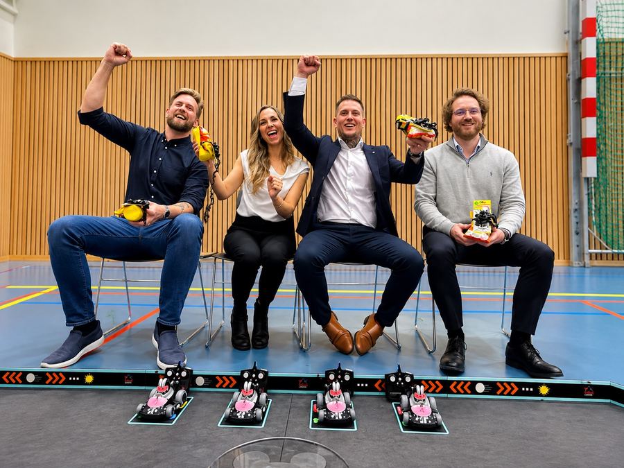 Fire deltakere jubler over de radiostyrte bilene på startstreken i en idrettshall
